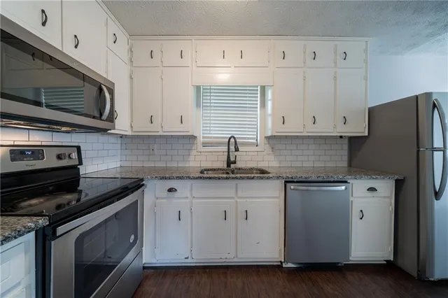 a kitchen with granite countertop white cabinets white stainless steel appliances and a sink