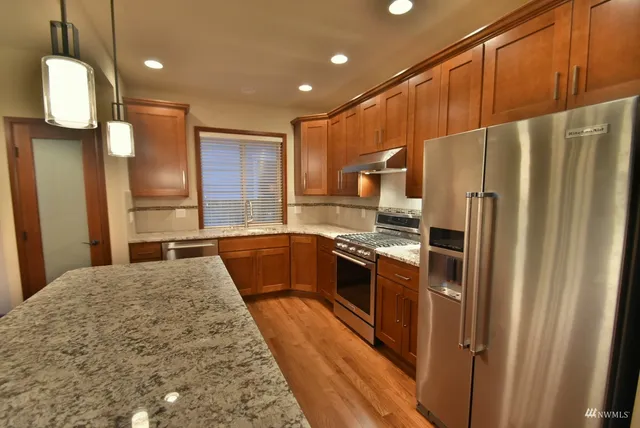 a kitchen with stainless steel appliances granite countertop a refrigerator a oven and a sink