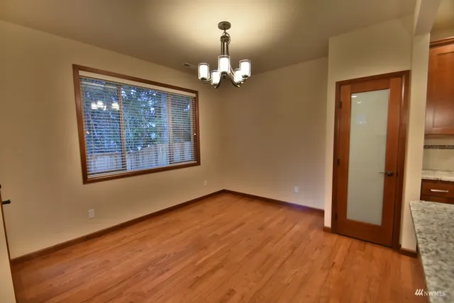 a view of an empty room with chandelier fan and wooden floor