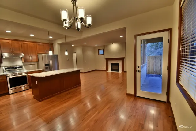 a large kitchen with stainless steel appliances granite countertop a large counter top and wooden floors