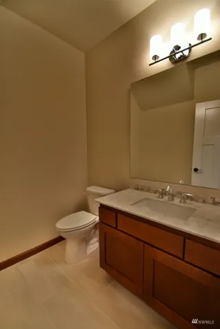 a bathroom with a granite countertop sink and a toilet
