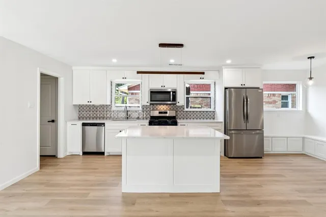 a kitchen with granite countertop a refrigerator oven a sink and dishwasher with wooden floor