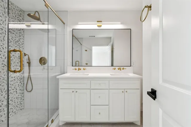 a bathroom with a double vanity sink mirror and shower