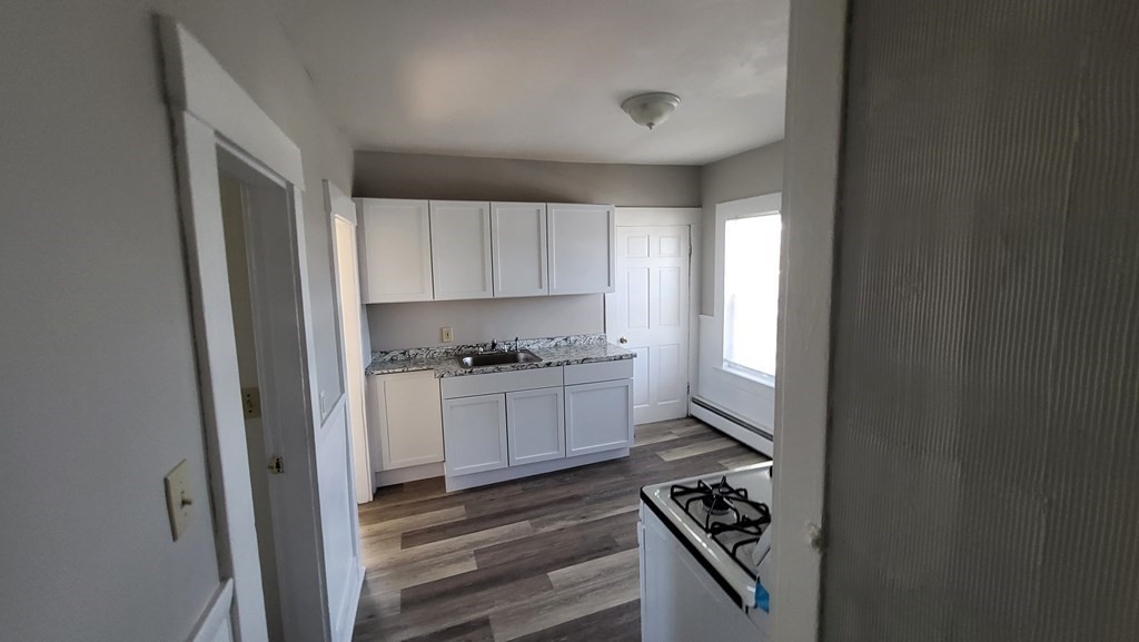 19 Delmont Avenue, Unit 19 Lowell, MA 01852 - Photo 6 of 14 a kitchen with granite countertop a stove cabinets and a sink