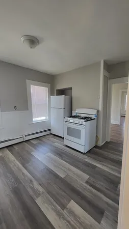 a view of kitchen and empty room with wooden floor