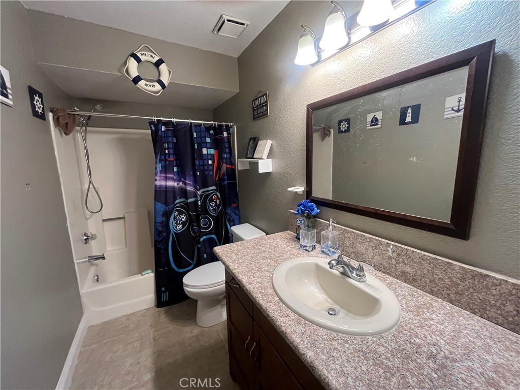 1491 Portrait Street Perris, CA 92571 - Photo 10 of 10 a bathroom with a granite countertop sink a toilet a mirror and shower