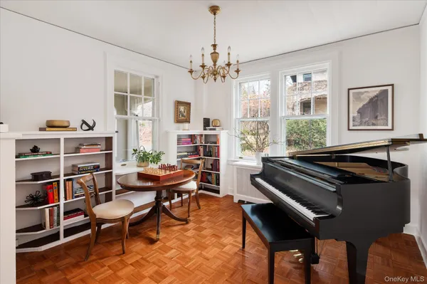 a living room with furniture a piano and a bookshelf