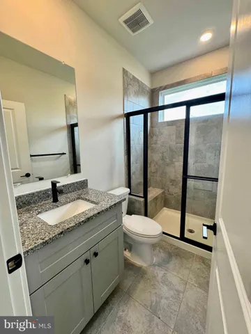 a bathroom with a granite countertop sink toilet and shower