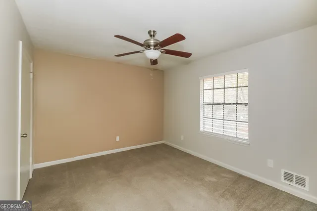 an empty room with windows and fan