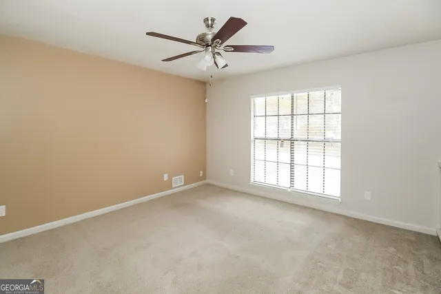 an empty room with a window and a fan