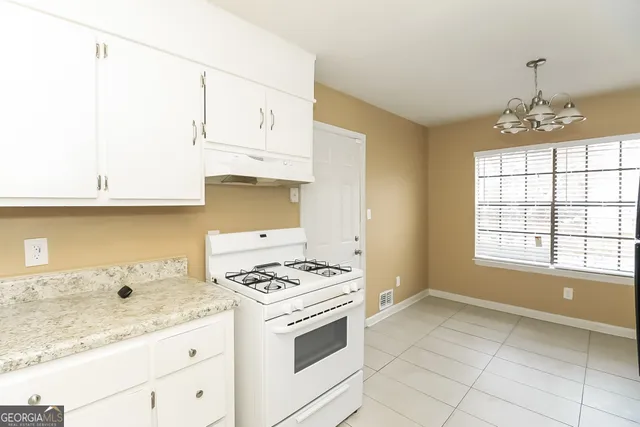 a kitchen with granite countertop a stove a sink dishwasher and white cabinets with wooden floor
