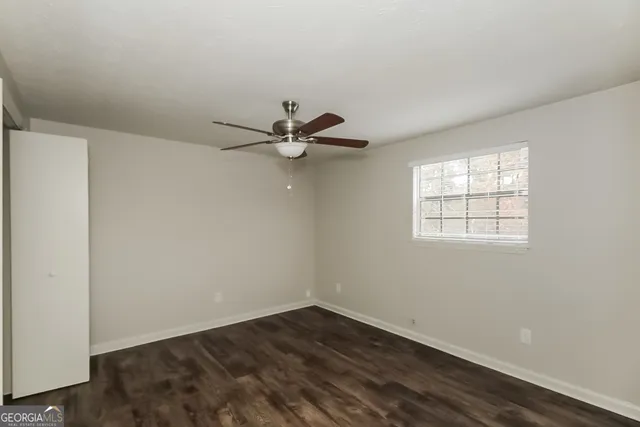 an empty room with a window and a ceiling fan
