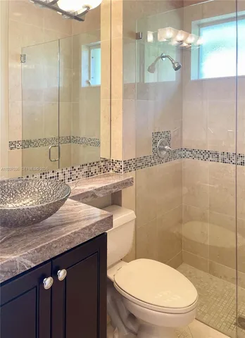 a bathroom with a granite countertop sink a mirror and a toilet