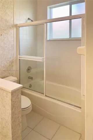 a bathroom with a granite countertop bathtub shower sink vanity and toilet