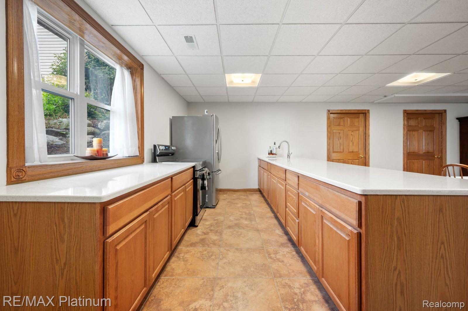 8922 McClements Road Brighton, MI 48114 - Photo 23 of 65 Lower Level Spacious kitchen featuring extensive wood cabinetry, light-toned countertops, and durable flooring