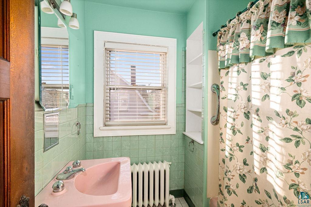 1505 North 19th Street Superior, WI 54880 - Photo 11 of 18 Bathroom featuring curtained shower, radiator heating unit, and tile walls