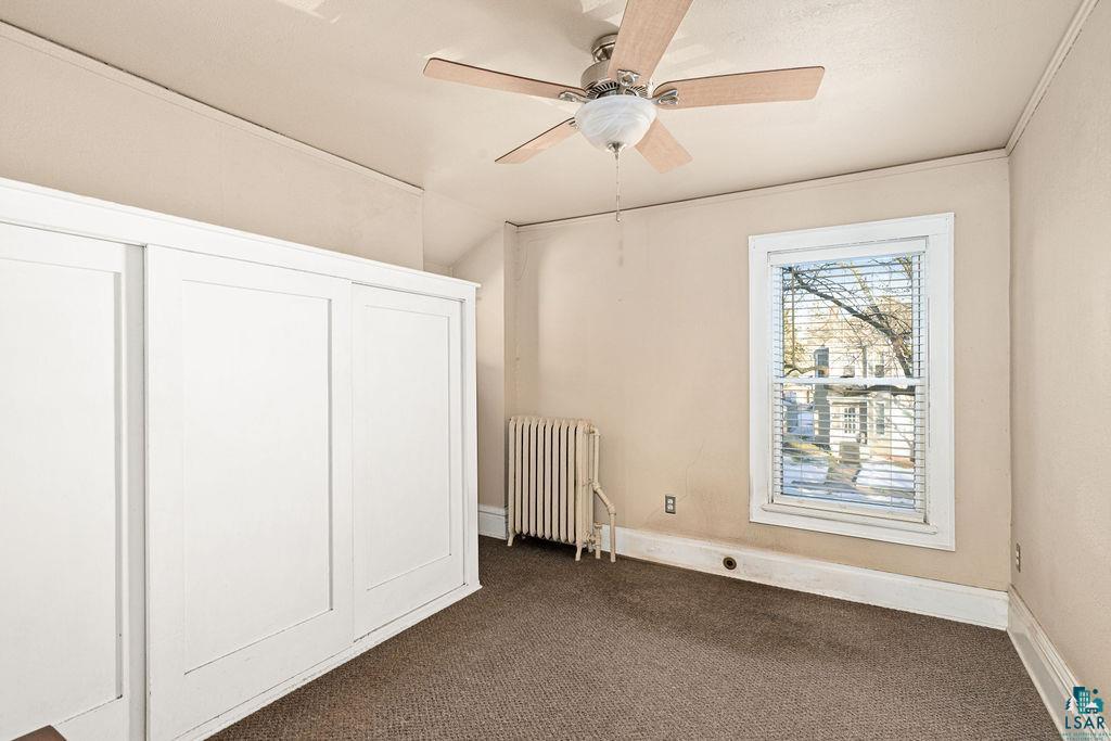 1505 North 19th Street Superior, WI 54880 - Photo 13 of 18 Unfurnished bedroom featuring radiator, dark colored carpet, and a ceiling fan