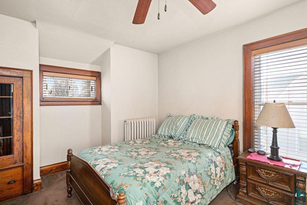 1505 North 19th Street Superior, WI 54880 - Photo 15 of 18 Bedroom featuring radiator heating unit, dark colored carpet, and ceiling fan