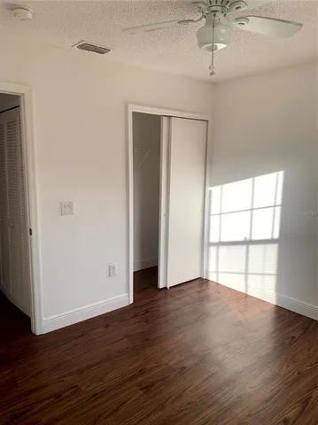 an empty room with wooden floor chandelier and windows