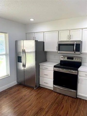 a kitchen with granite countertop a refrigerator and a stove top oven