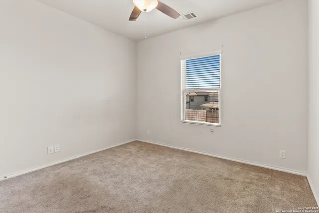 an empty room with a window and a ceiling fan