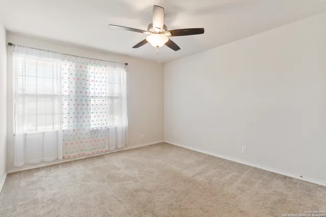 an empty room with a ceiling fan and windows