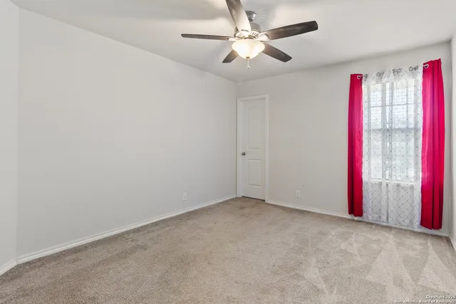an empty room with fan and a window