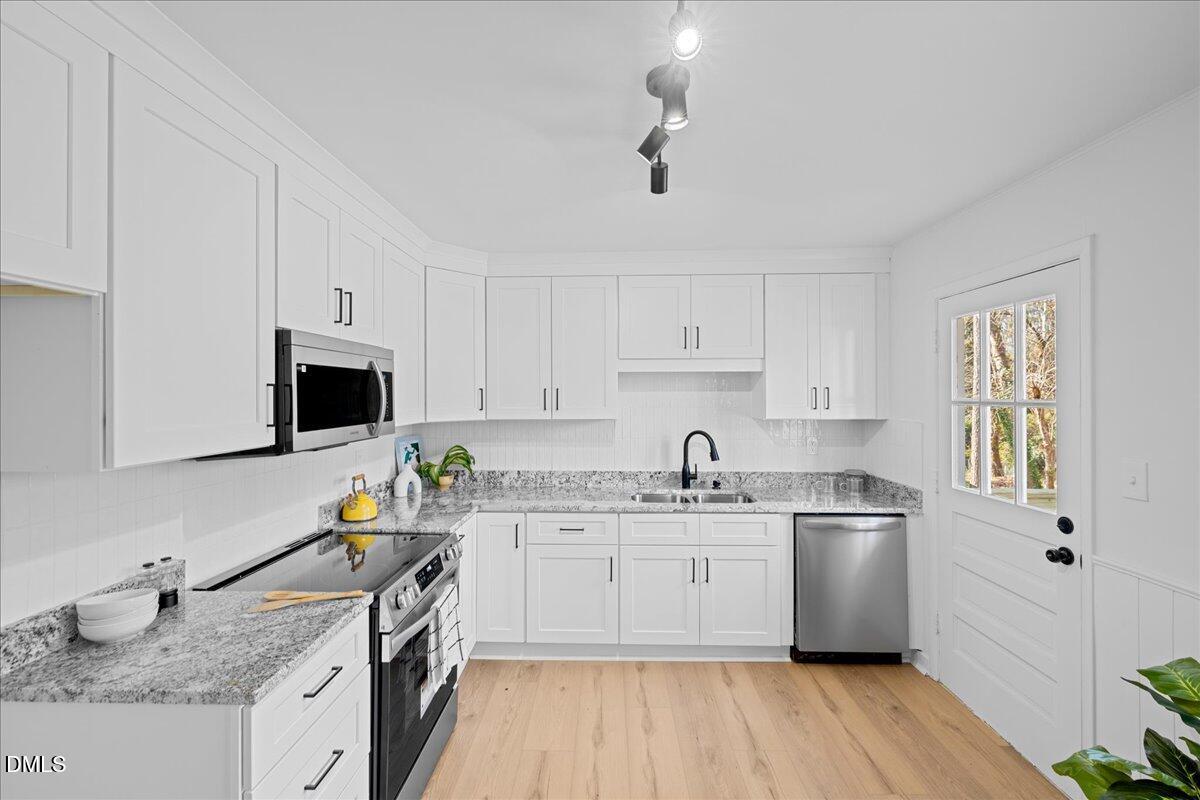 1406 Valley Road Garner, NC 27529 - Photo 12 of 39 a kitchen with a sink white cabinets and white appliances