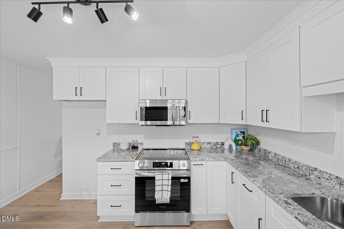 1406 Valley Road Garner, NC 27529 - Photo 13 of 39 a kitchen with stainless steel appliances granite countertop white cabinets a stove a sink and dishwasher