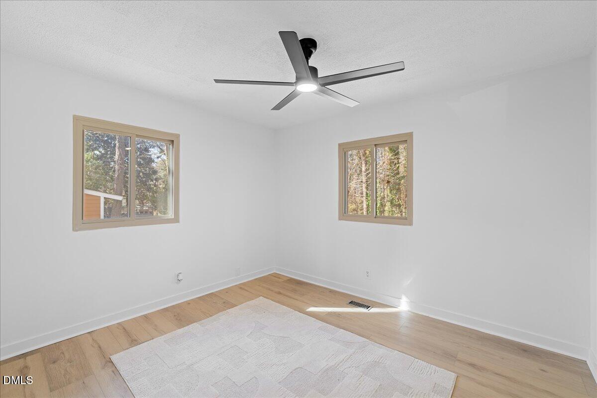 1406 Valley Road Garner, NC 27529 - Photo 21 of 39 a view of an empty room with wooden floor and a ceiling fan