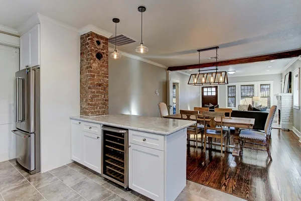 a kitchen with stainless steel appliances granite countertop a refrigerator a sink dishwasher a dining table and chairs with wooden floor