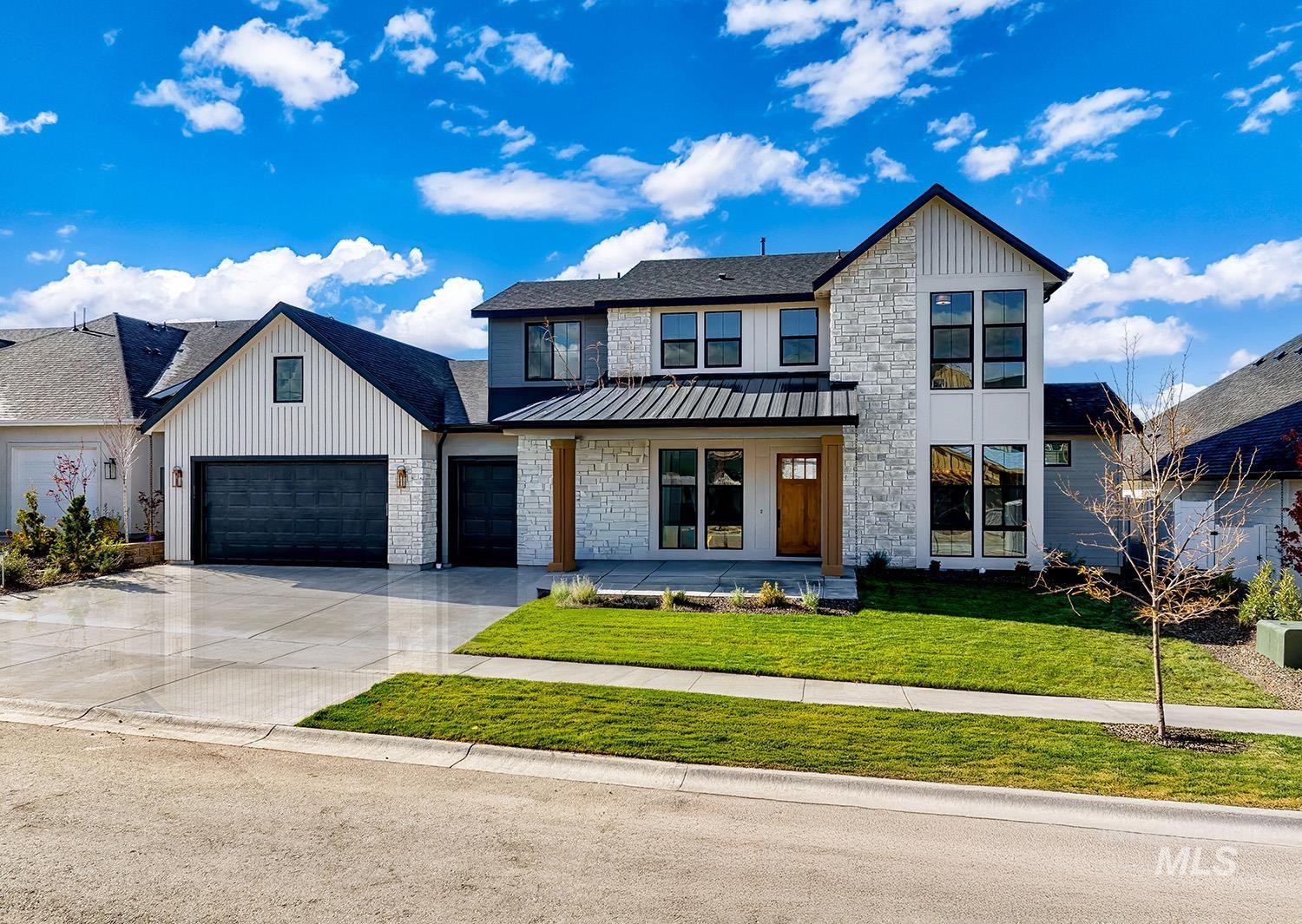 Modern inspired farmhouse featuring a front yard, driveway, covered porch, and stone siding