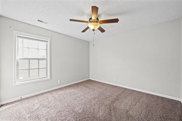 an empty room with windows and fan