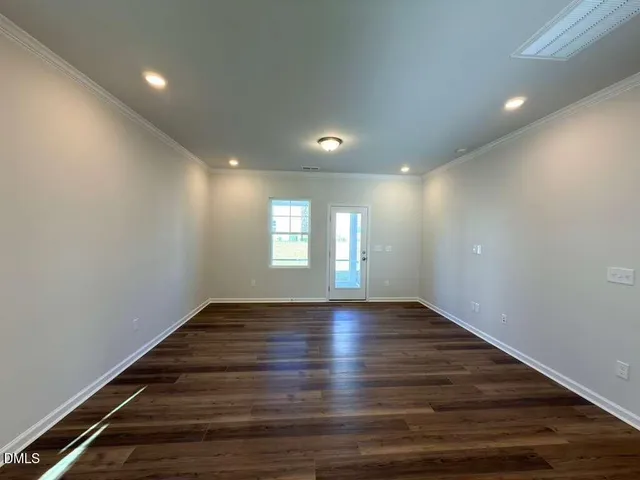 a view of an empty room with wooden floor and window