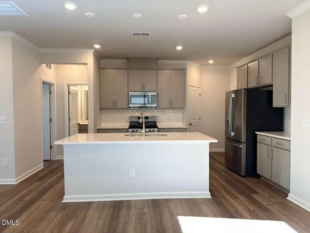 a kitchen with stainless steel appliances granite countertop a refrigerator a stove and a sink