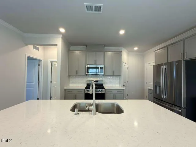 a large white kitchen with kitchen island a sink stainless steel appliances and cabinets