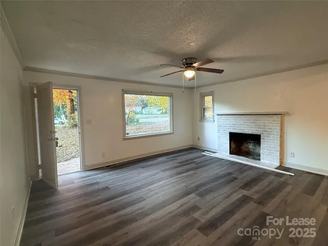 an empty room with wooden floor a fireplace and windows
