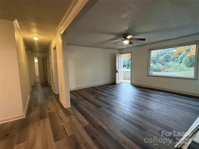 a view of a room with wooden floor ceiling fan and windows