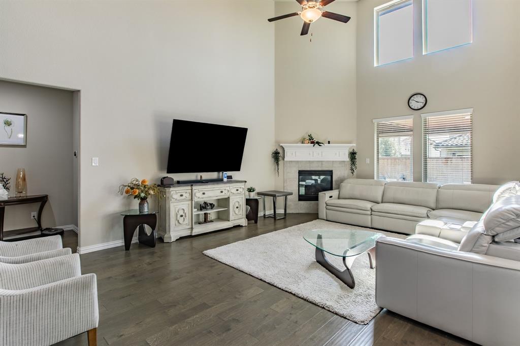 2521 Maidenhair Road Frisco, TX 75033 - Photo 2 of 39 Two-story living area featuring wood-finish flooring, a corner fireplace with a white mantel, and high windows