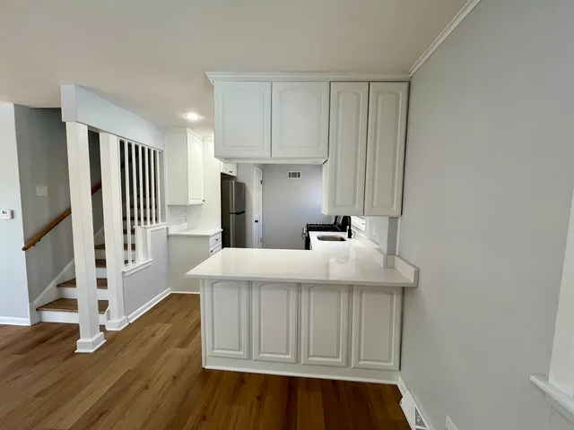 a kitchen with a sink a refrigerator and wooden floor