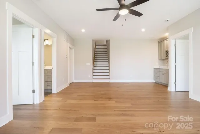a view of an empty room with a window and kitchen view