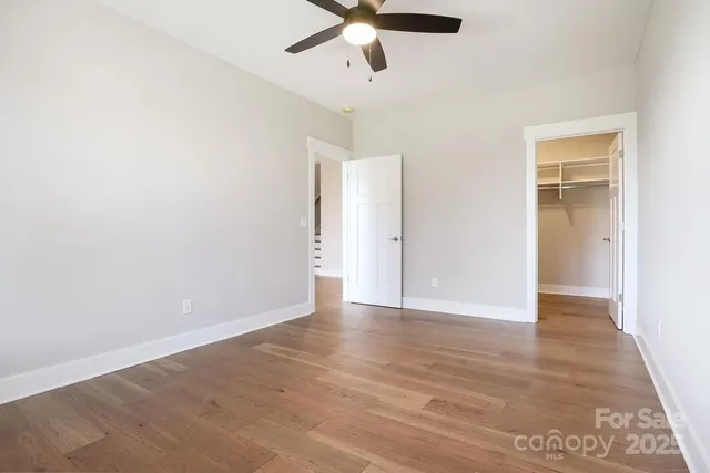 an empty room with wooden floor ceiling fan and windows