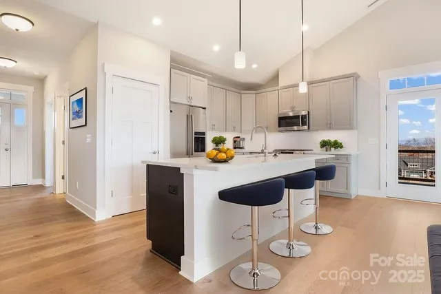 a kitchen with stainless steel appliances kitchen island granite countertop a table chairs and a refrigerator