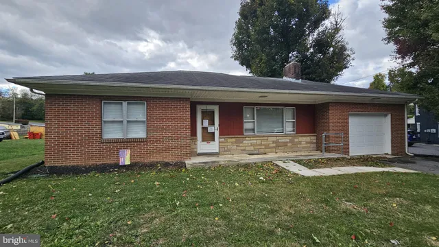 a brick house next to a yard with a large tree