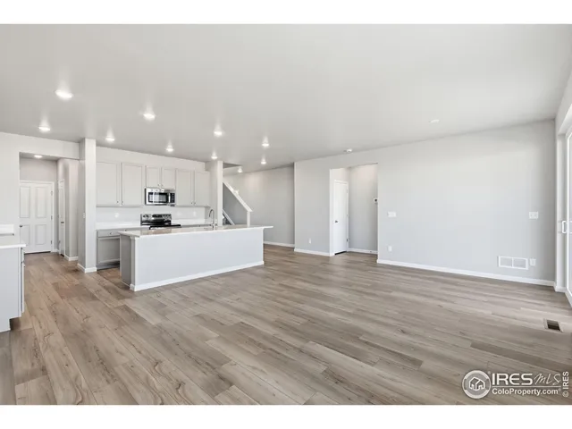 a view of kitchen with kitchen island wooden floors wooden cabinets and refrigerator