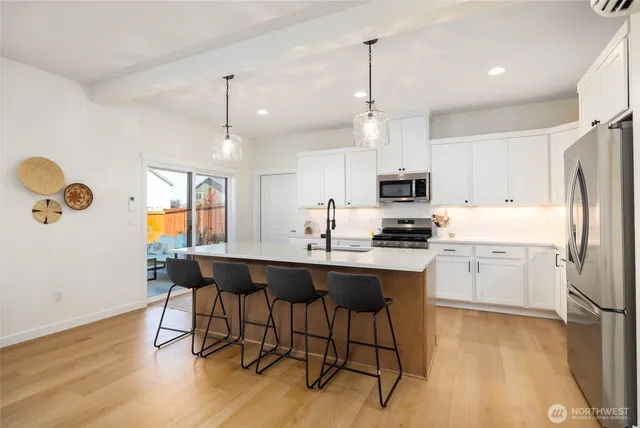 a kitchen with a refrigerator a stove a sink and white cabinets