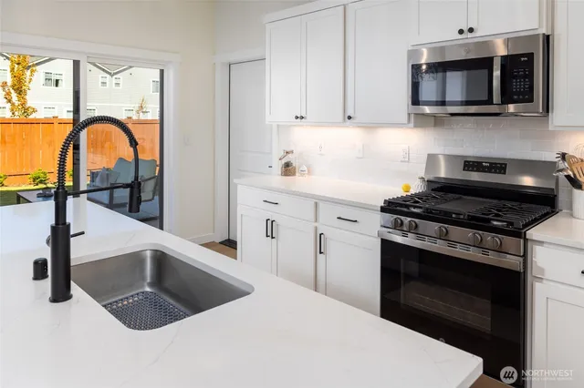 a kitchen with kitchen island granite countertop a sink stainless steel appliances and cabinets