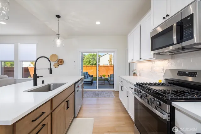 a kitchen with a sink a center island a counter space stainless steel appliances and cabinets