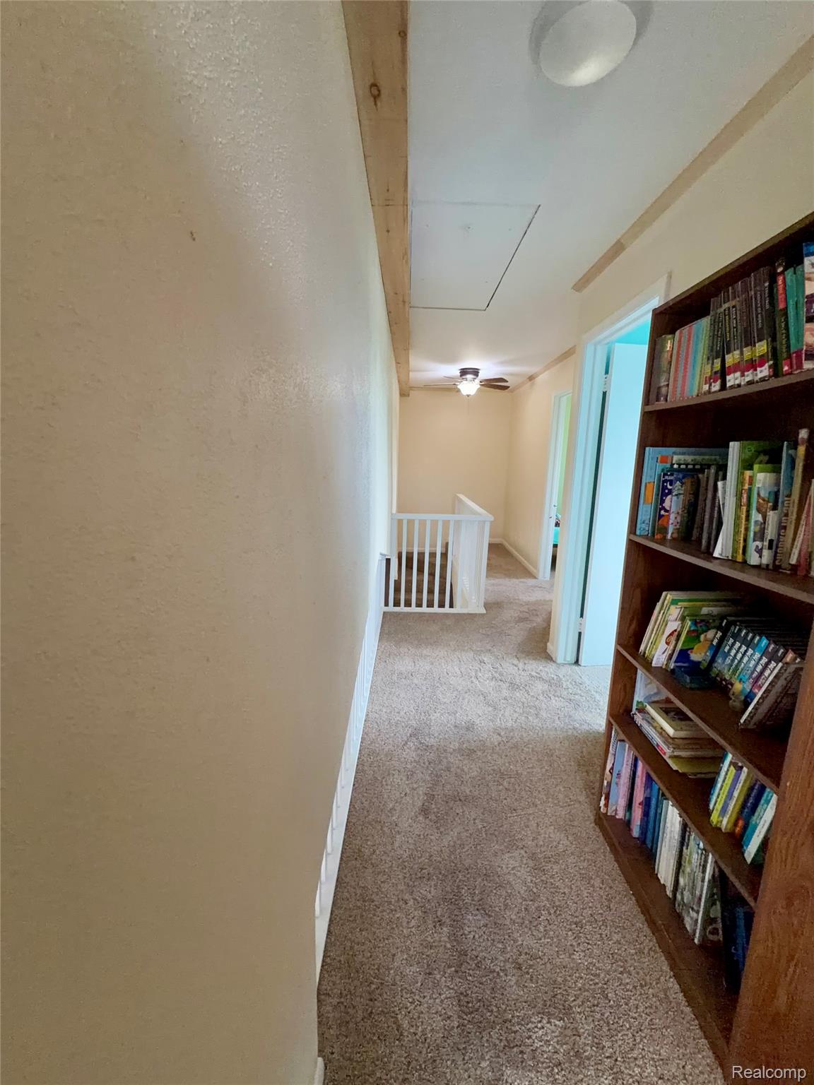 10865 Norman Road Yale, MI 48097 - Photo 18 of 23 Hallway featuring plush carpeting, a built-in bookshelf, and architectural wood beam details