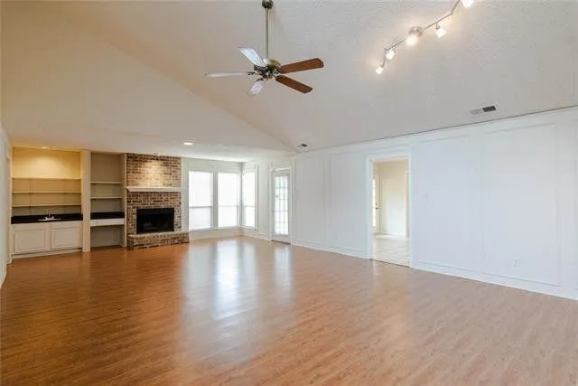 a view of an empty room with a window and wooden floor